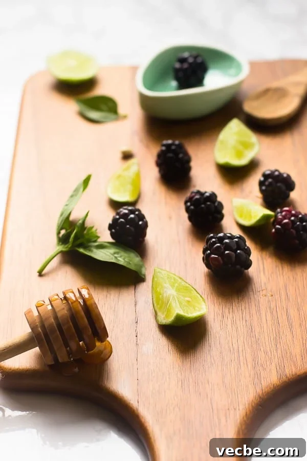 Homemade Blackberry Limeade Recipe with 5 Ingredients 3 Blackberries, lime wedges and honey on a chopping board.