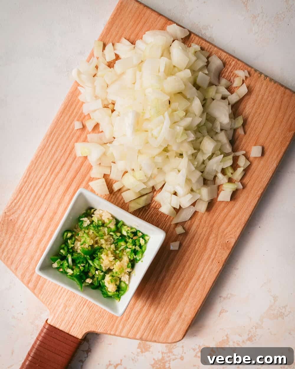 Creamy Vegan Pumpkin Curry with Crispy Tofu 12 chopped onions, garlic and serrano on a wooden cutting board.