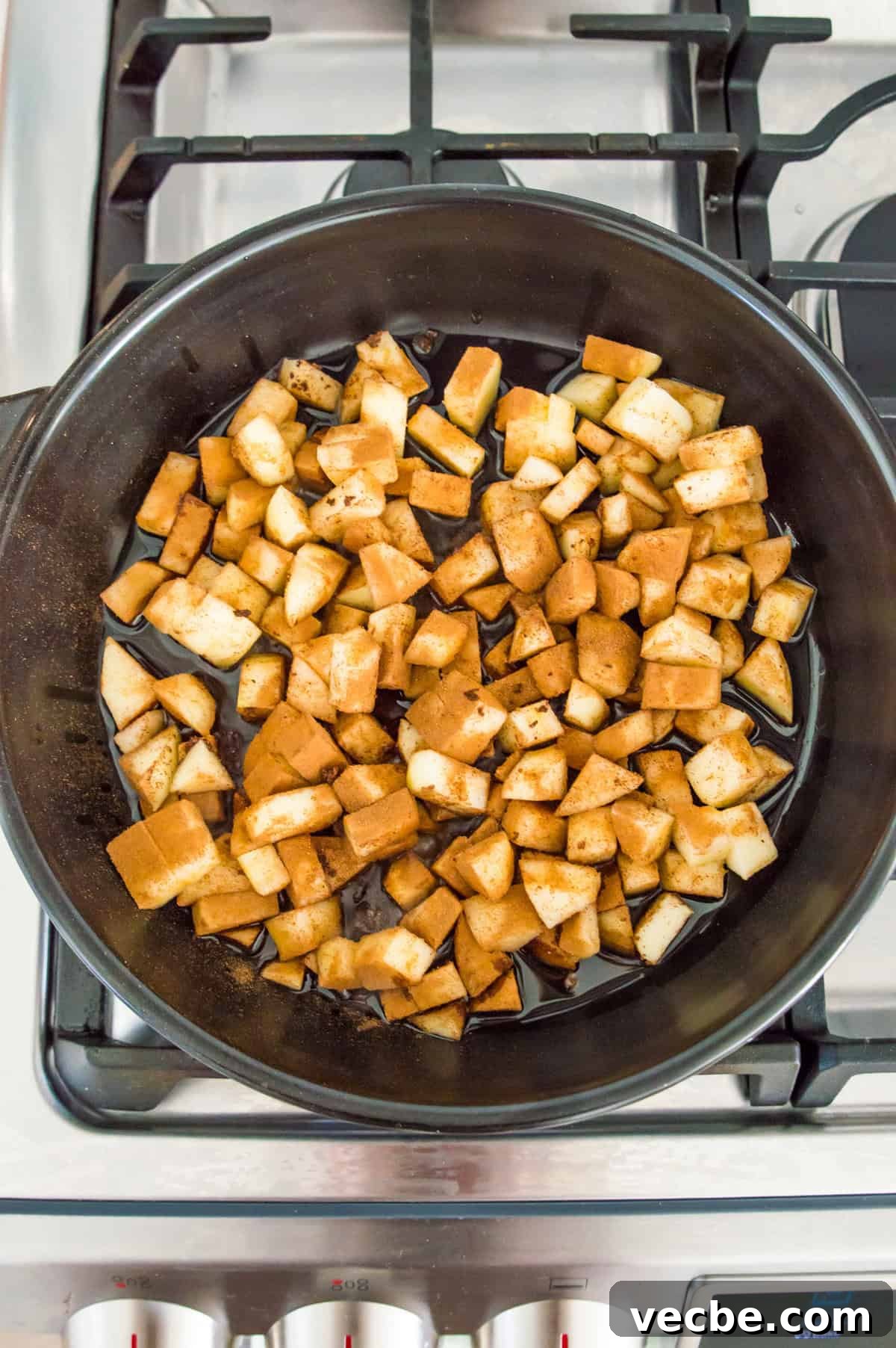 Apple Pie Bars Gluten Free Vegan and Paleo 6 Apple pieces cooking in a black pan on a stovetop.