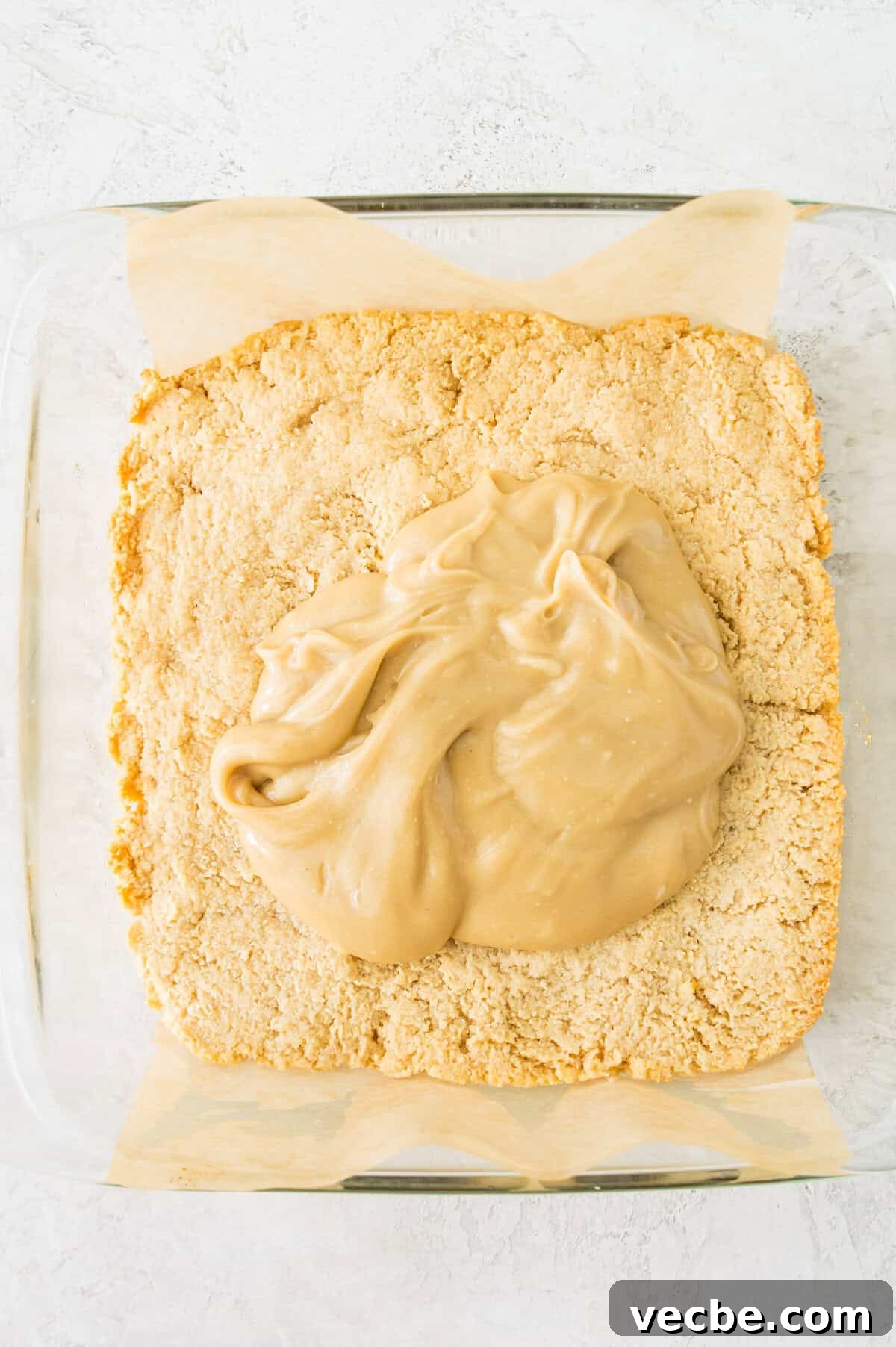 Apple Pie Bars Gluten Free Vegan and Paleo 8 A shortbread crust in a square baking pan with caramel spread over it.