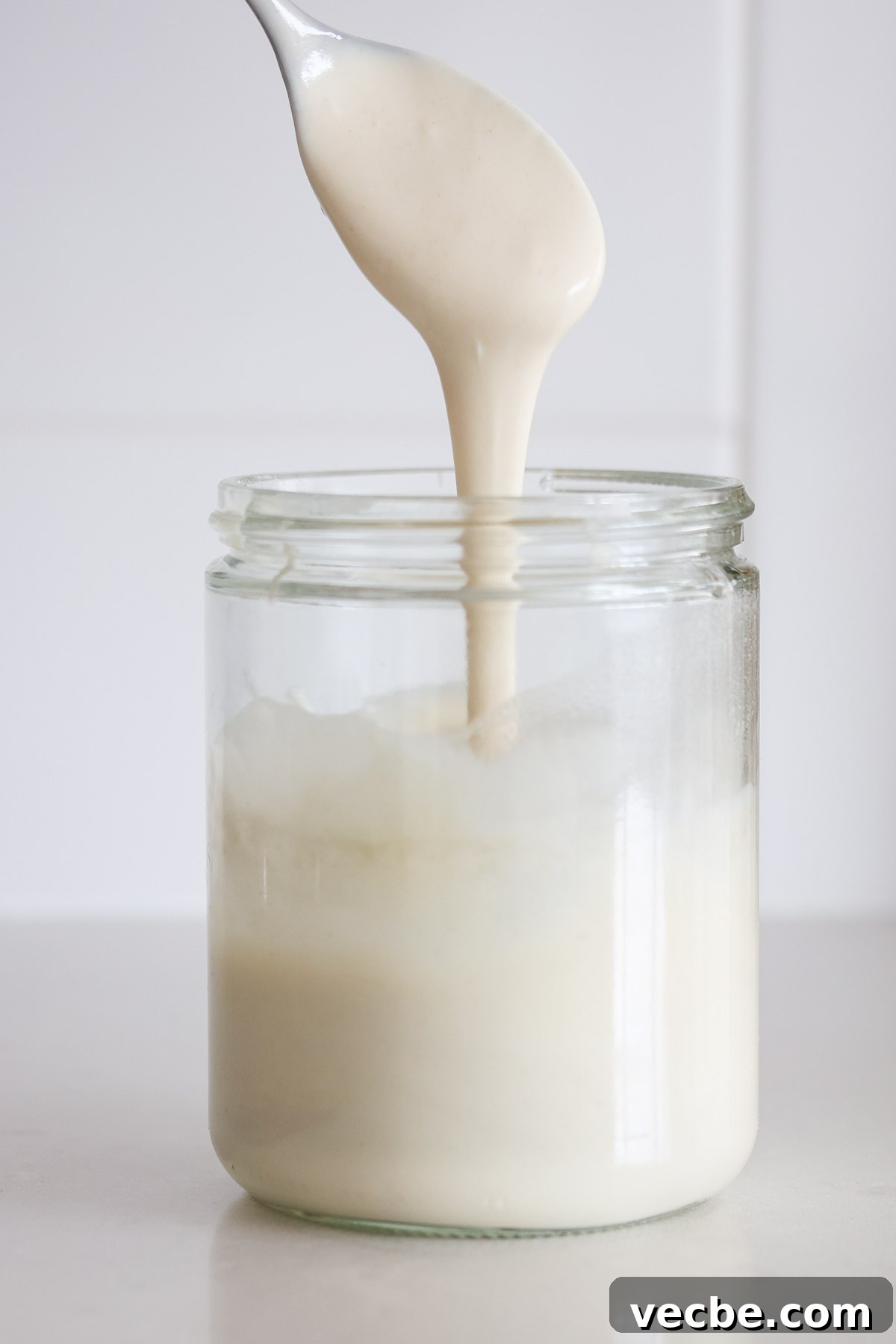 Why Your Sourdough Starter Is Weak and How to Revive It 2 Thin sourdough starter pouring of a spoon into a jar.