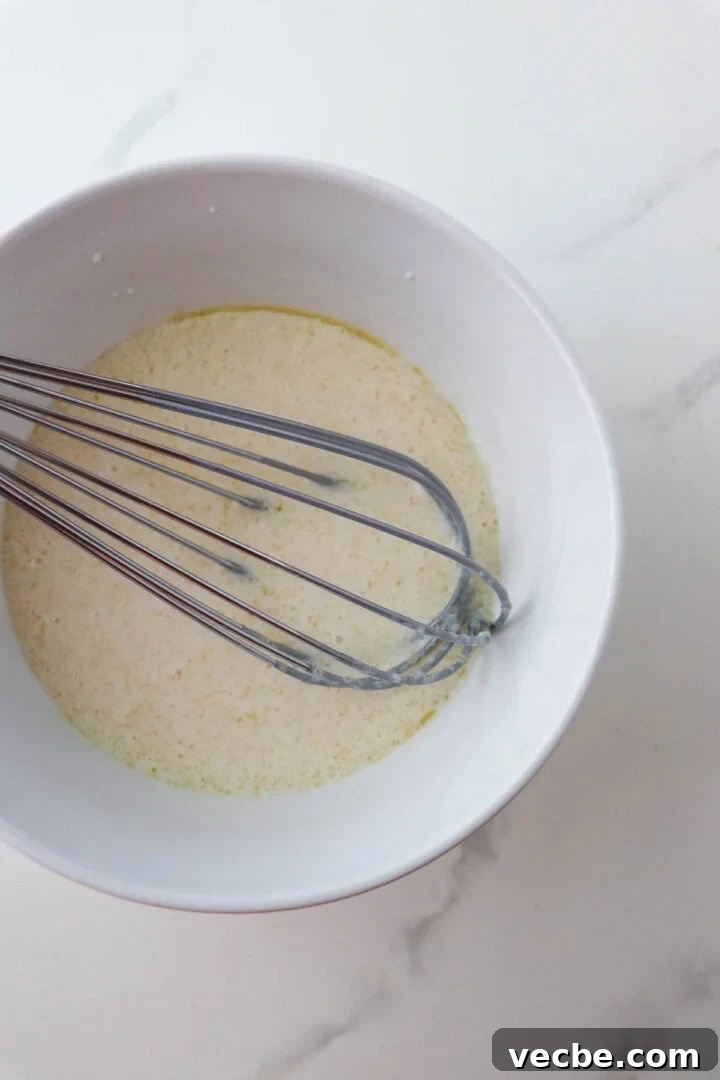 Homemade Soft and Tender Buttermilk Bread Recipe 5 Liquid ingredient for Soft and Tender Buttermilk Bread in a bowl with a whisk.