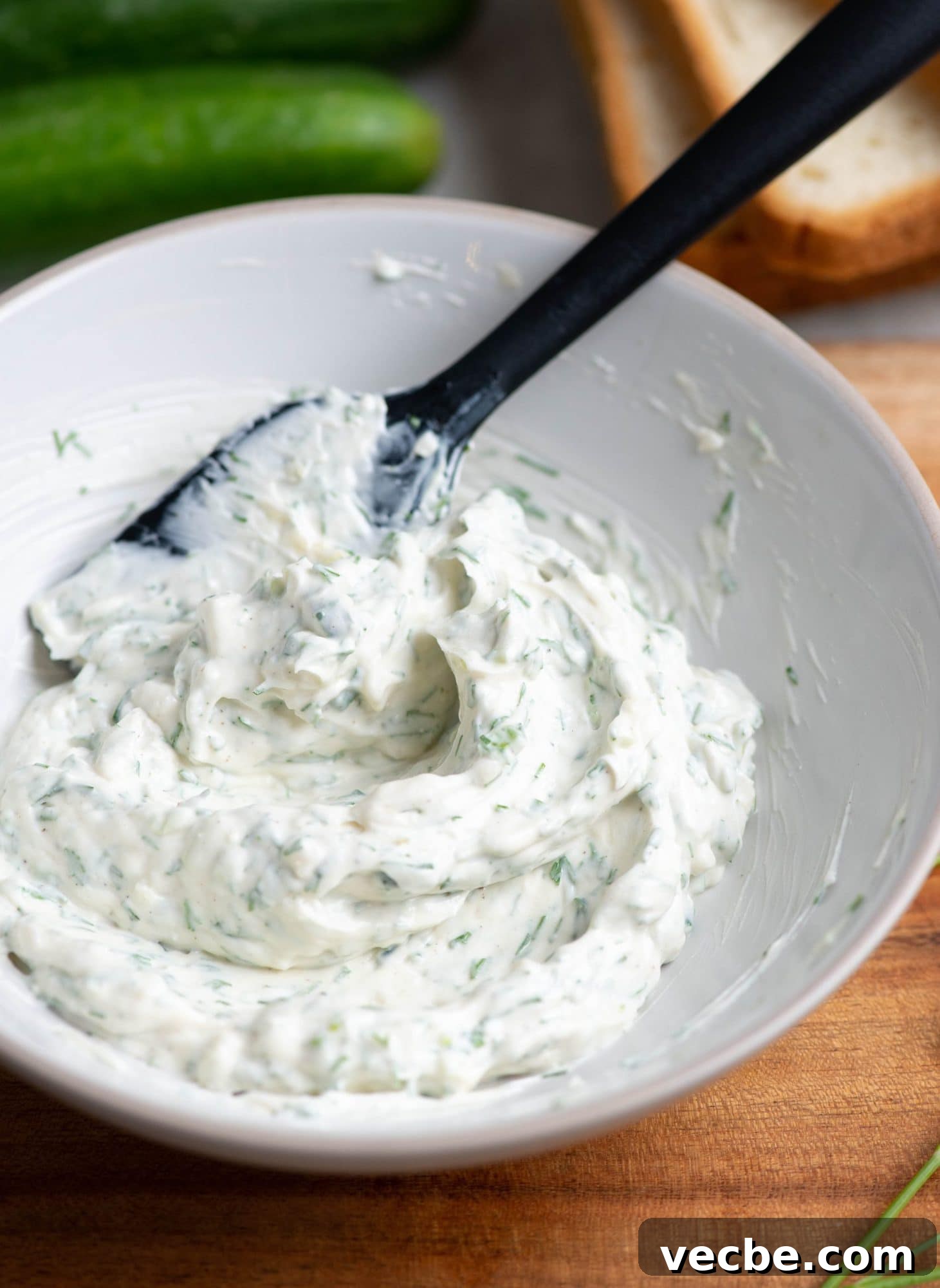 Herby Cream Cheese Spread for Sandwiches Herby cream cheese spread made in a small bowl and mixes with a black spatula.