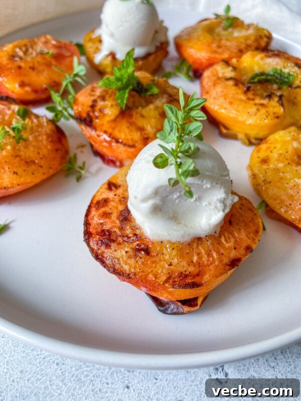 Caramelized Air Fryer Pineapple Recipe 3 Grilled peach halves on a white plate, topped with scoops of vanilla ice cream and garnished with fresh herbs.