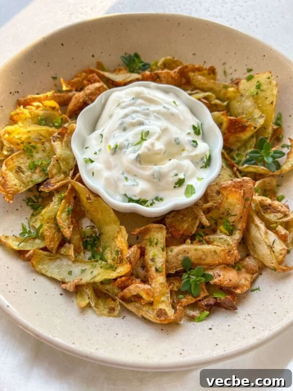 Caramelized Air Fryer Pineapple Recipe 6 A plate of crispy potato skins garnished with herbs and served with creamy white dipping sauce.