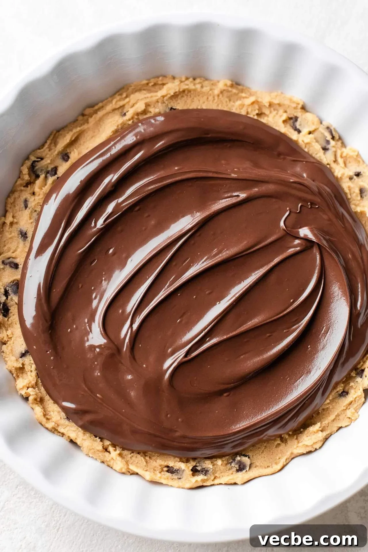 Giant Nutella-Stuffed Chocolate Chip Cookie Recipe 8 Nutella spread on top of cookie dough in pie dish with little border around the edges