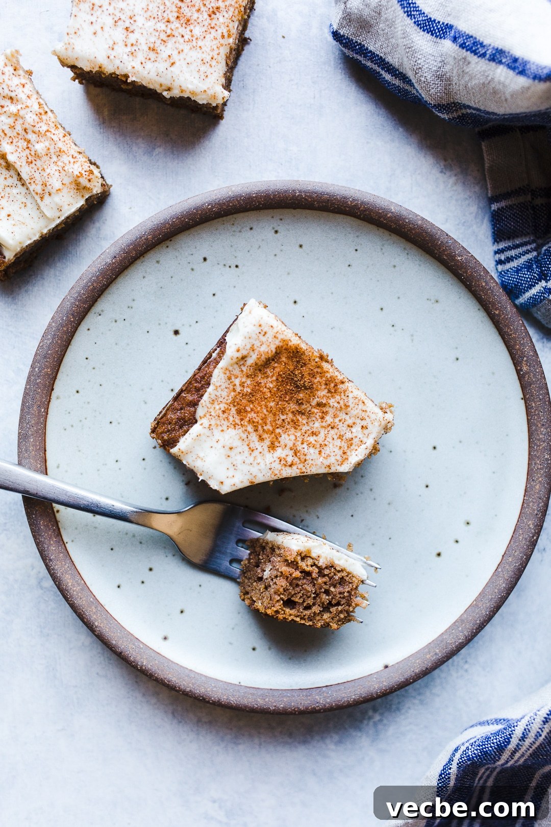 Gluten-Free Apple Recipes: 10+ Desserts, Snacks and More 3 A piece of applesauce cake topped with cream cheese frosting on a rustic plate.