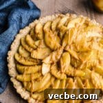 Gluten-Free Apple Recipes: 10+ Desserts, Snacks and More 6 An apple tart drizzled with caramel sit on a wooden surface with a blue cloth.
