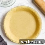 healthy pie crust made with almond flour in a glass pie dish with a rolling pin in the corner