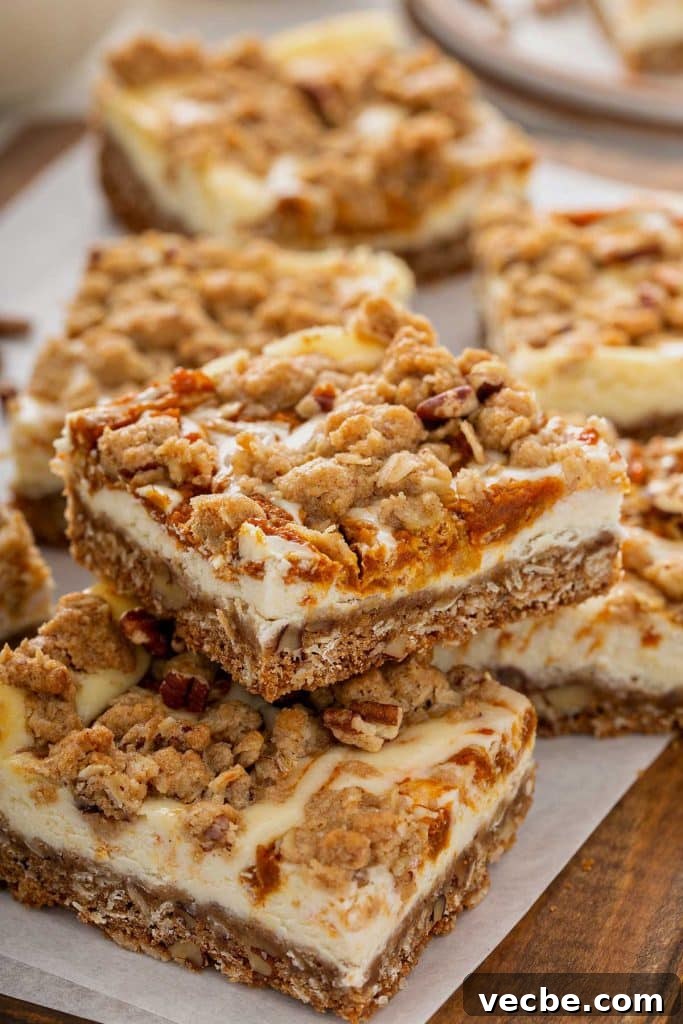 Pumpkin Cheesecake Bars with Creamy Swirl 2 Swirled oat and pumpkin cheesecake bars on parchment paper.