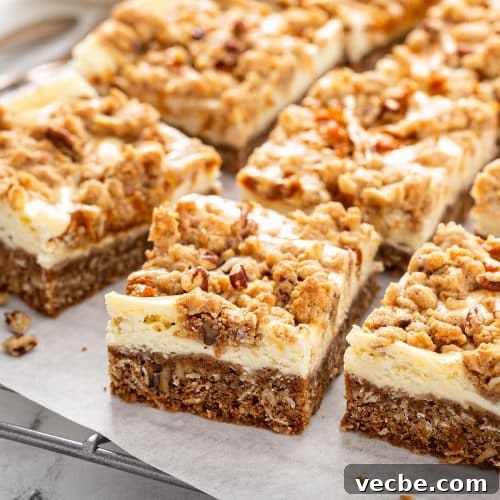 Pumpkin Cheesecake Bars with Creamy Swirl 15 Pumpkin cheesecake bars with crumb topping on a cooling rack.