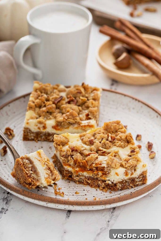 Pumpkin Cheesecake Bars with Creamy Swirl 4 Pumpkin cheesecake bars served on a plate.
