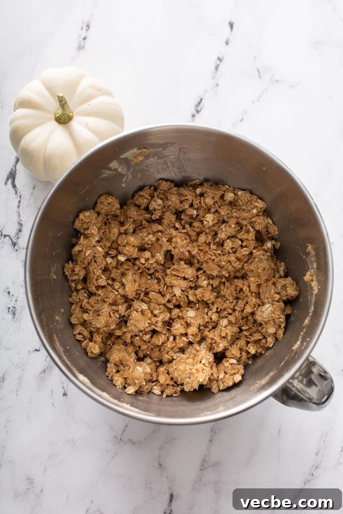 Pumpkin Cheesecake Bars with Creamy Swirl 7 Oat crust ingredients mixed with butter in a stand mixer bowl.