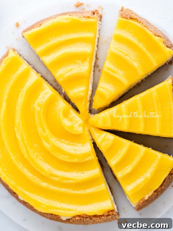 Lemon Meringue Ice Cream Pie Recipe 5 Lemon cheesecake topped with lemon curd cut into slices on a marble cake plate with white background.