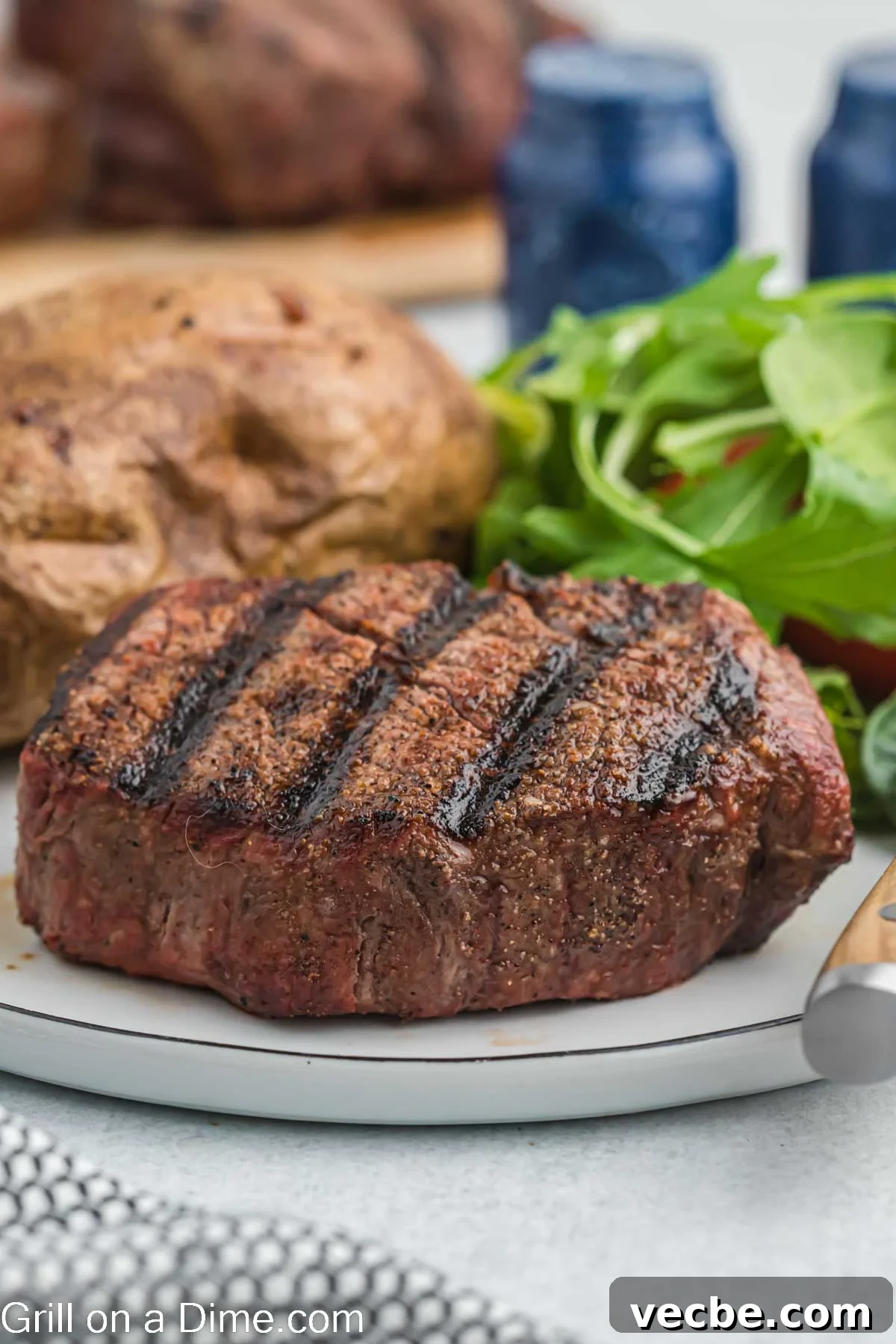 Grilled Filet Mignon Recipe: Tender, Juicy Steak 2 Filet Mignon on a plate with a baked potato and salad