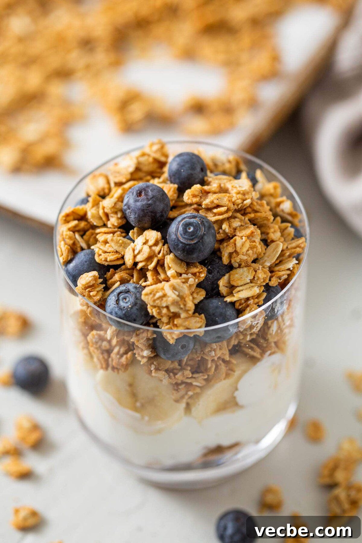 Homemade Peanut Butter Granola Recipe 2 Yogurt, banana and granola parfait topped with blueberries in a glass jar.