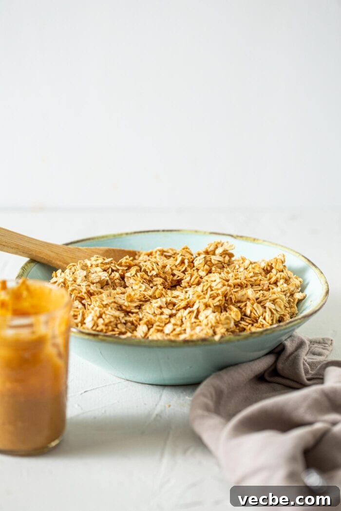 Homemade Peanut Butter Granola Recipe 4 Mixed, raw granola in a bowl with a wooden spoon.