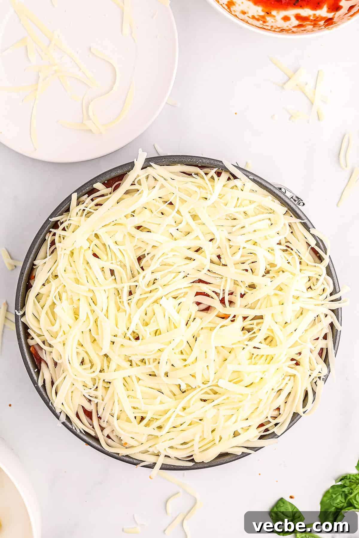 Cheese topped honeycomb pasta before baking mozzarella cheese on top of rigatoni pasta in a pan