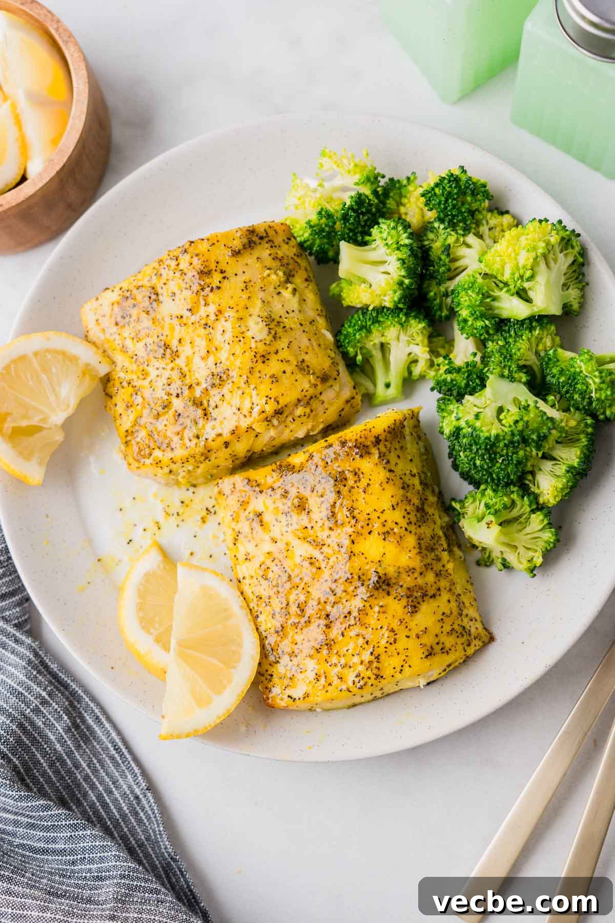 Air Fryer Mahi Mahi with Lemon Garlic 2 air fryer mahi mahi with broccoli and lemon wedges on a white plate.