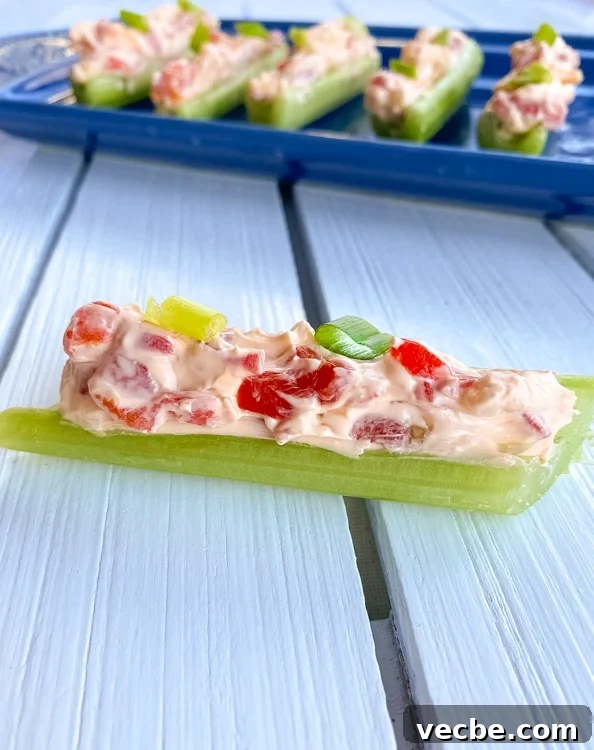 15 No-Bake Snack Recipes You Can Make in Minutes 3 Stick of celery filled with cream cheese and pimento peppers on a table.