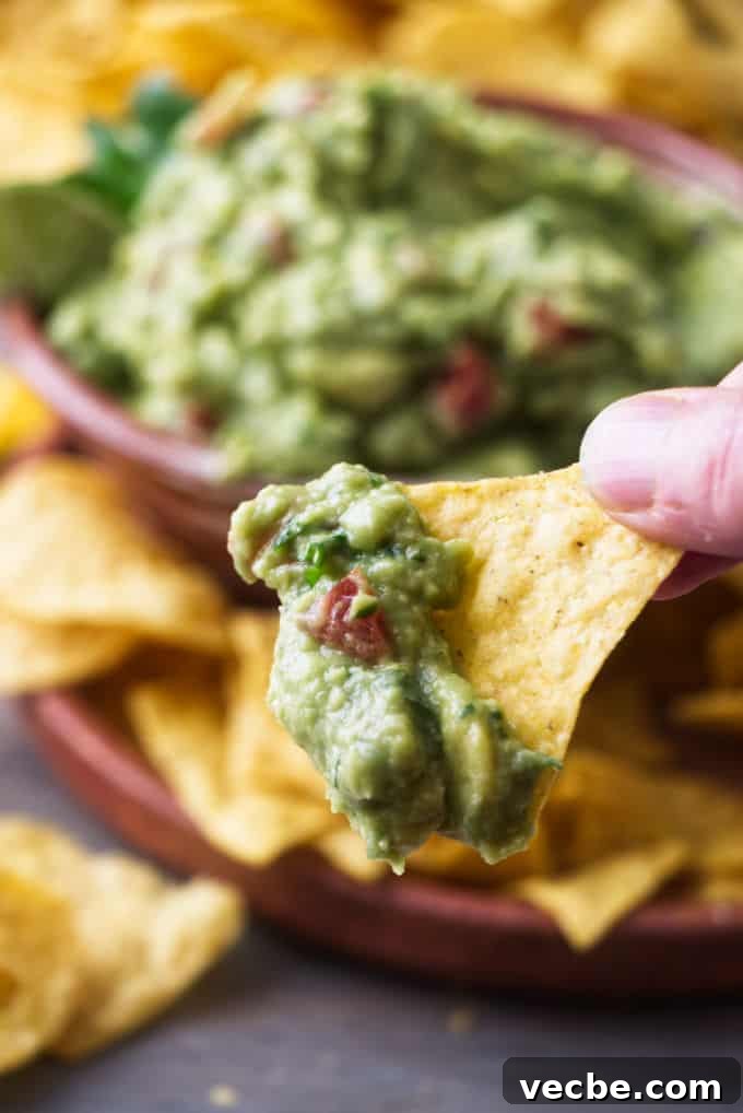 Zesty Tomato and Pepperoncini Guacamole Recipe 5 A corn chip dipped in guacamole with tomatoes.