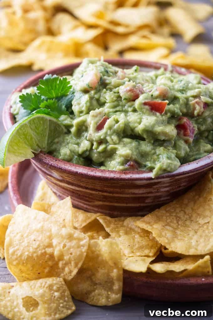 Zesty Tomato and Pepperoncini Guacamole Recipe 6 A serving dish of guacamole surrounded by corn chips.