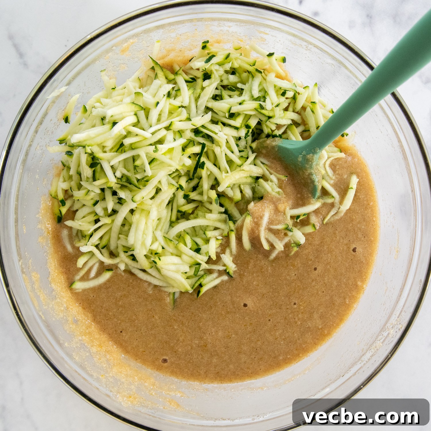 Gluten-Free Almond Flour Zucchini Bread: Secret Moist Recipe 6 zucchini being stirred into the bread batter.