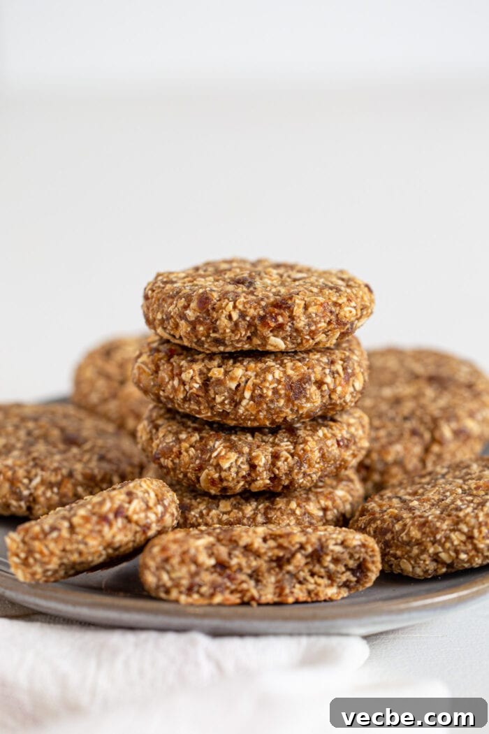 Vegan Tahini Date Cookies Recipe 6 4 oat date cookies stacked on a plate. More cookies sit around the stack.