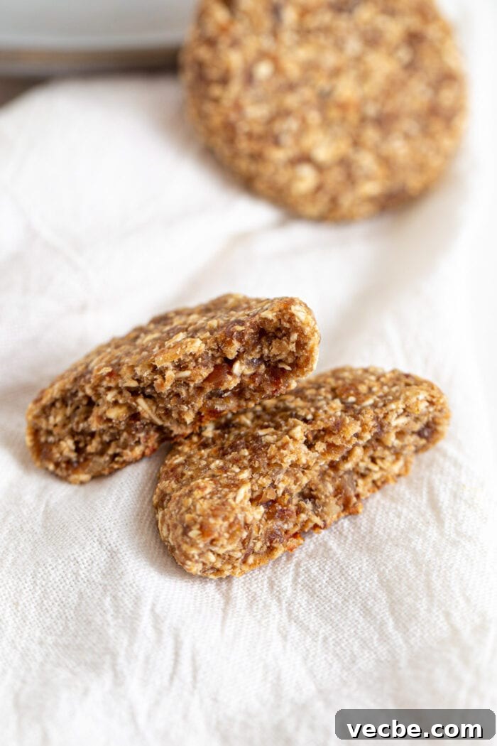 Vegan Tahini Date Cookies Recipe 7 Cookie broken in half to show inside. Cookie rests on a white dish towel.