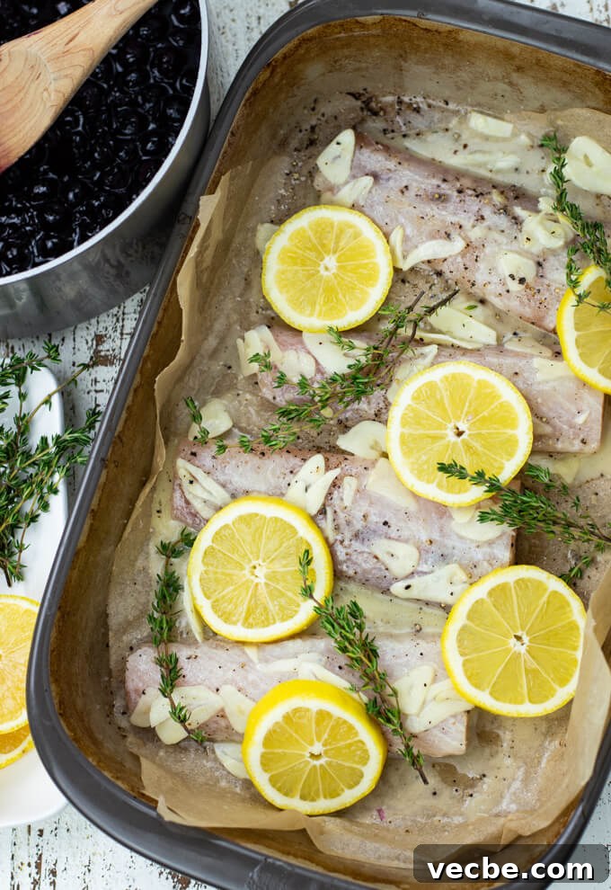 Baked Mahi Mahi with Fresh Blueberry Sauce 5 A casserole dish with uncooked mahi mahi and slices of lemon and fresh sprigs of thyme sit on the fish.