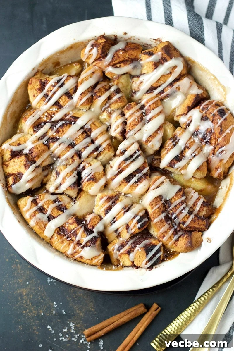 Mini Cinnamon Apple Cobbler Bites 2 Cinnamon Bites Apple Cobbler in a white rimmed dish, striped dish towel, and cinnamon stick.