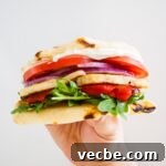 Grilled Halloumi Sandwich with Roasted Pepper and Spinach 5 A hand holding up a halloumi sandwich.
