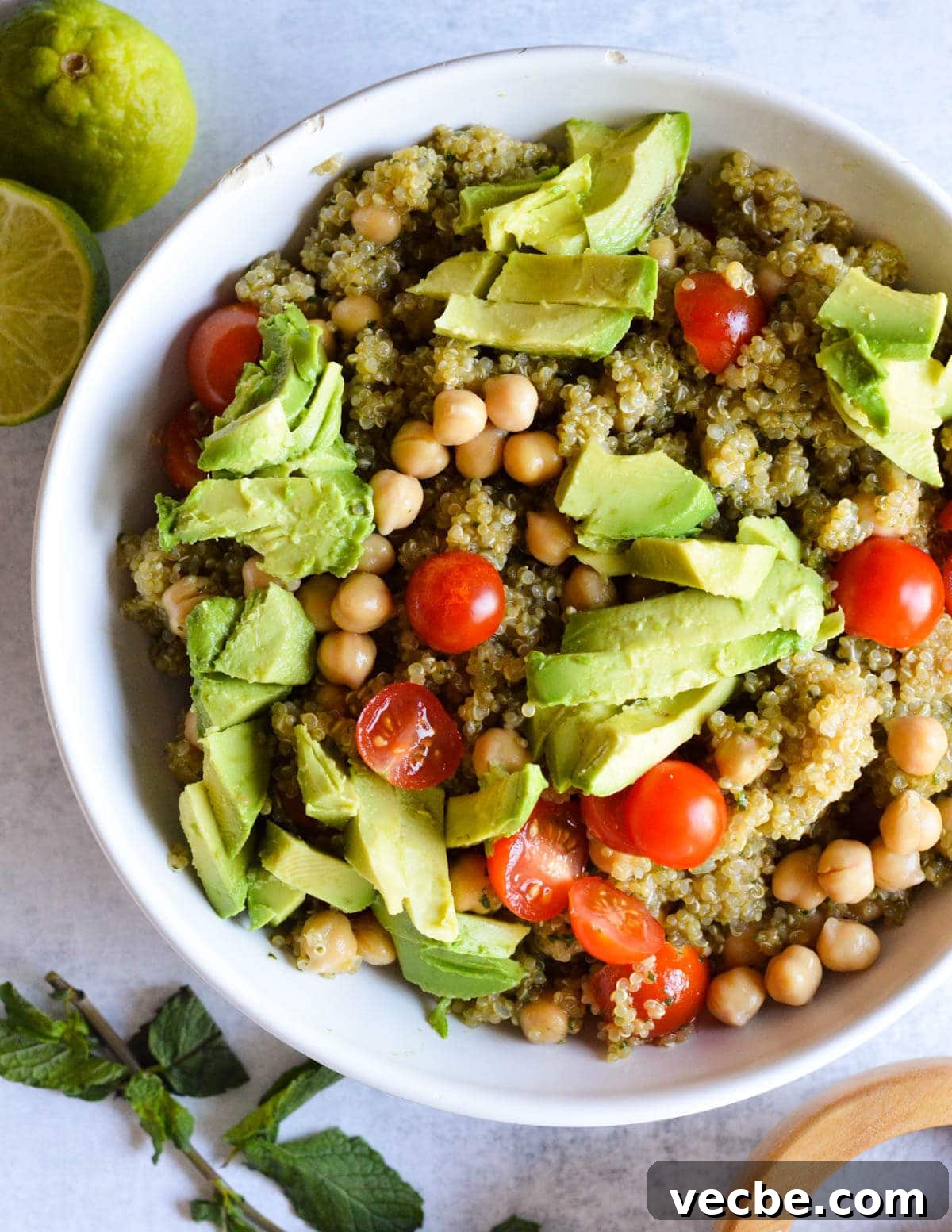 Herbed Quinoa Salad with Avocado and Chickpeas 2 a bowl of quinoa salad with sliced avocado and tomatoes on top.