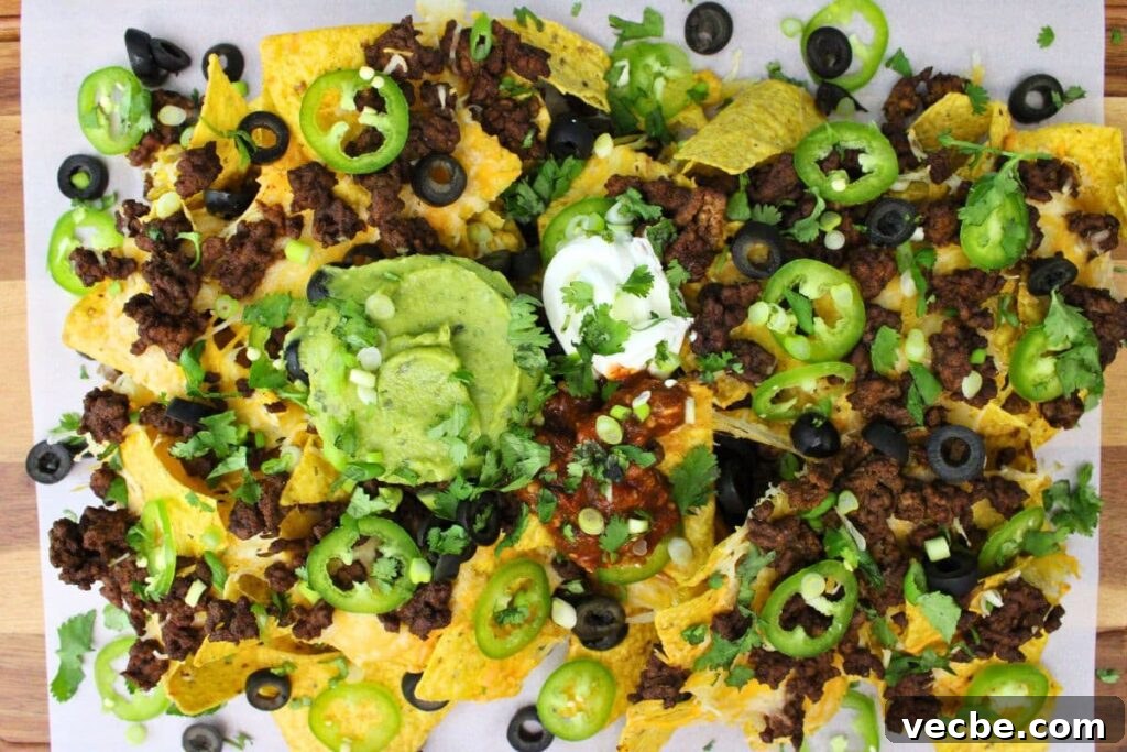 Crispy Air Fryer Ground Beef Nachos for Game Day 8 overhead view of air fryer nachos with ground beef, guacamole, and sour cream
