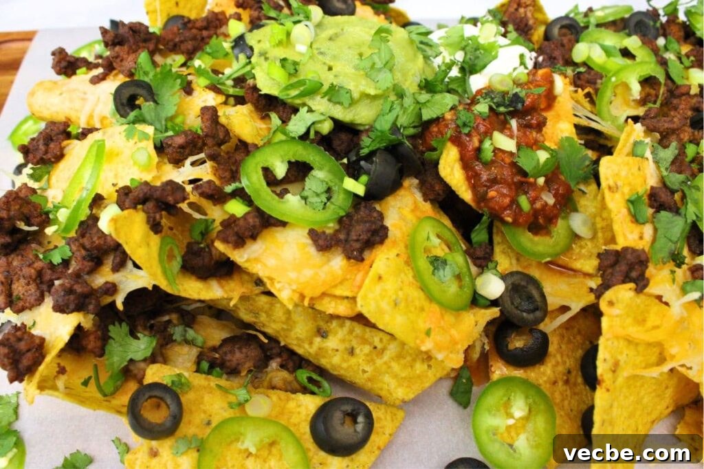 Crispy Air Fryer Ground Beef Nachos for Game Day 9 closeup of air fryer nachos topped with beef, jalapenos, olives, guacamole, and sour cream