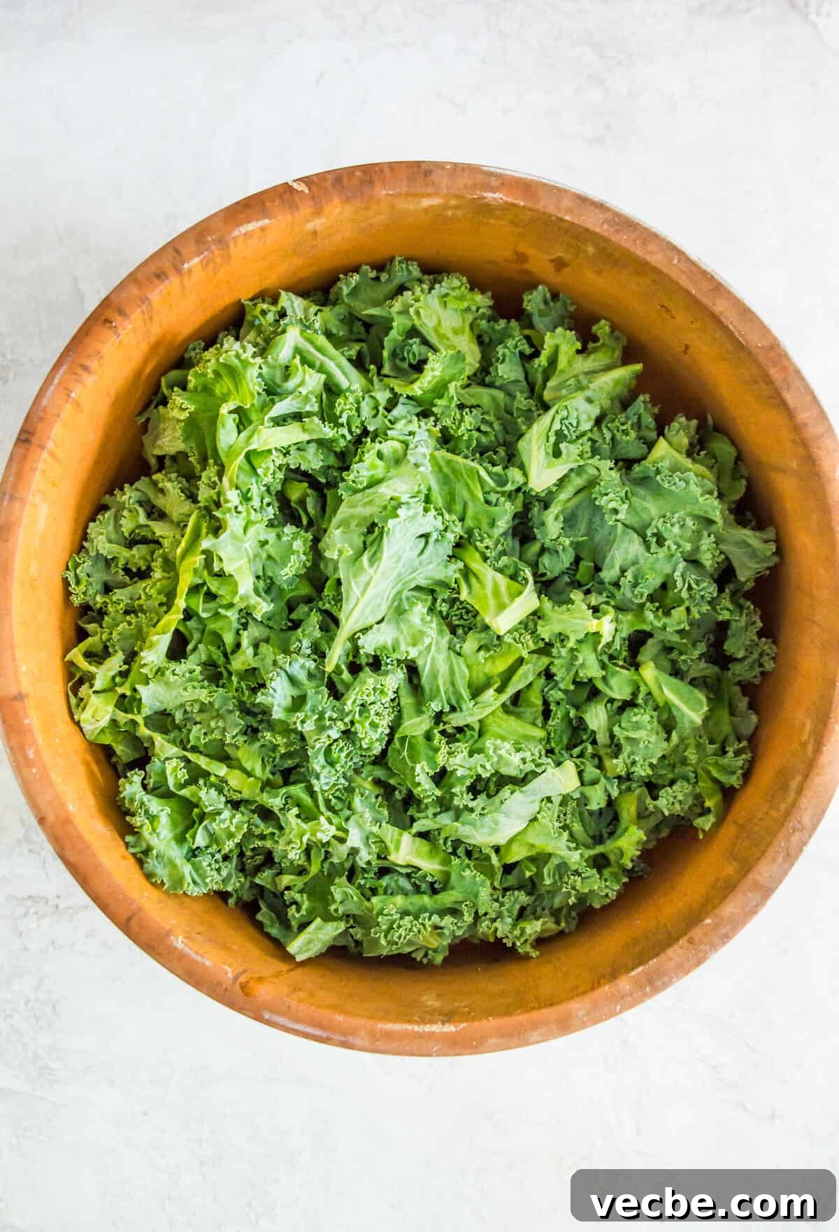 Cabbage-Free Kale Slaw with Apples and Carrots 3 Ripped kale in a large wooden bowl.