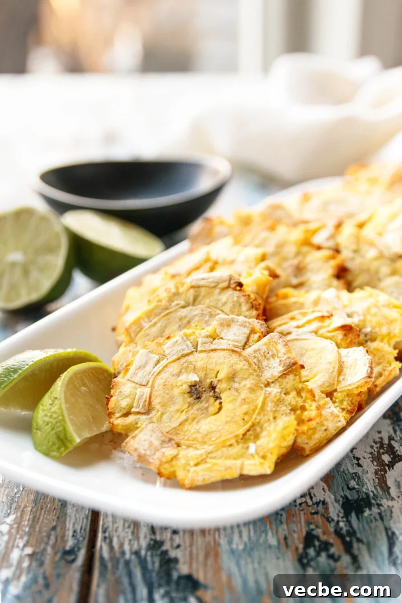 Air Fryer Tostones Cuban Fried Plantains 2 plated air fryer tostones on a rectangular white plate with lime wedges ready to enjoy