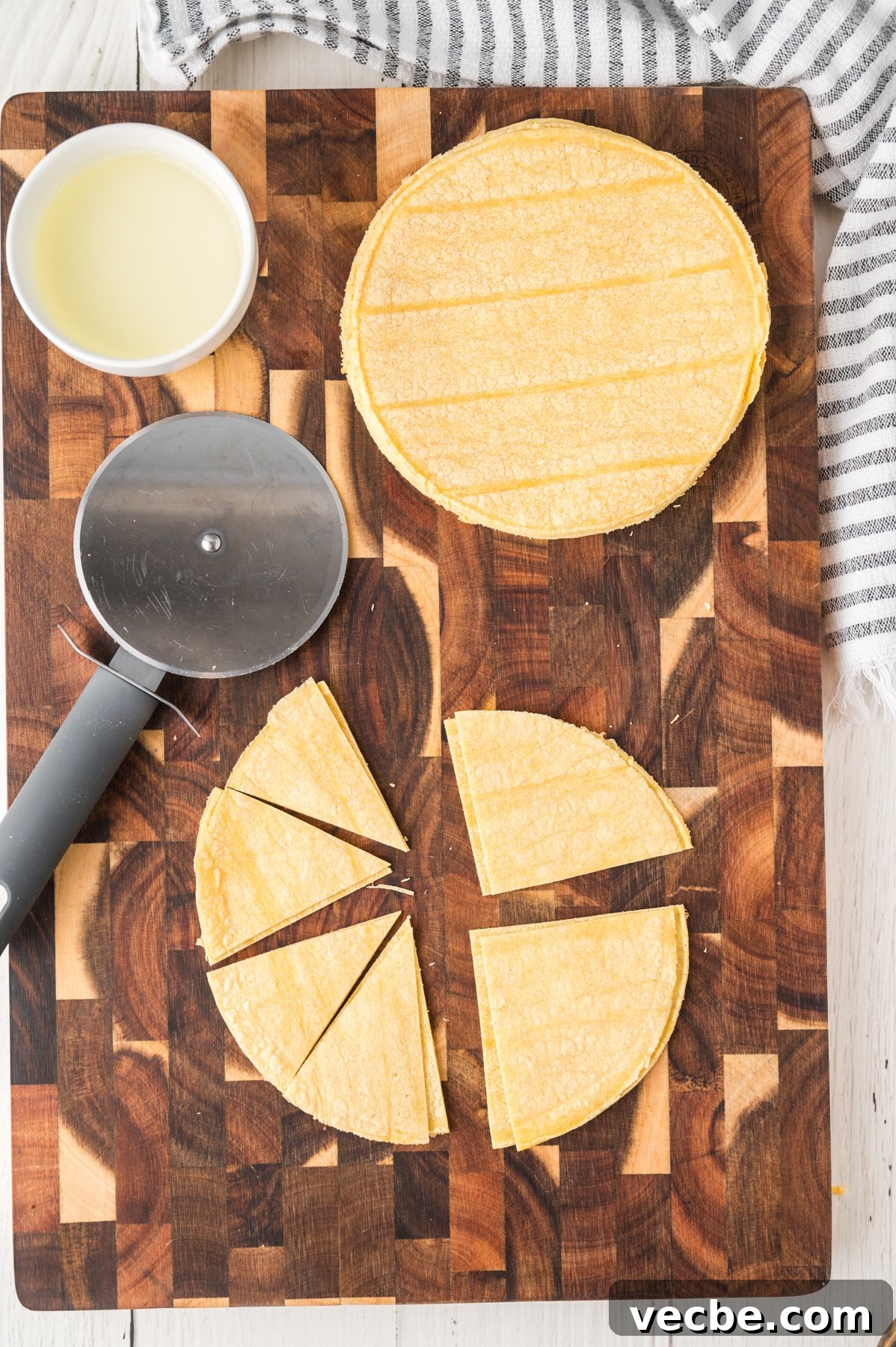 Crispy Baked Corn Tortilla Chips Recipe 4 A cutting board topped with corn tortillas that are being cut into triangles - Hostess At Heart
