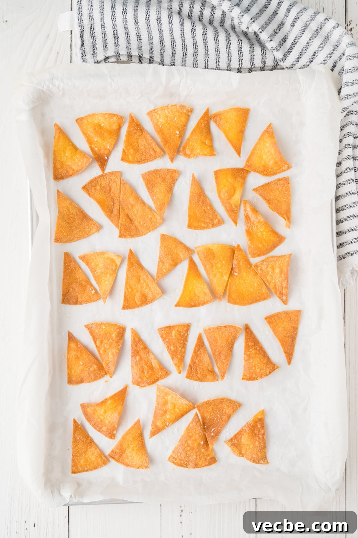 Crispy Baked Corn Tortilla Chips Recipe 6 Top down view of a single layer of baked tortilla corn chips on a baking sheet - Hostess At Heart