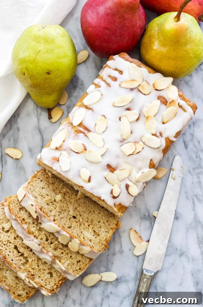 Almond-Glazed Pear Loaf Recipe 3 pear bread with almond glaze on a countertop with a knife