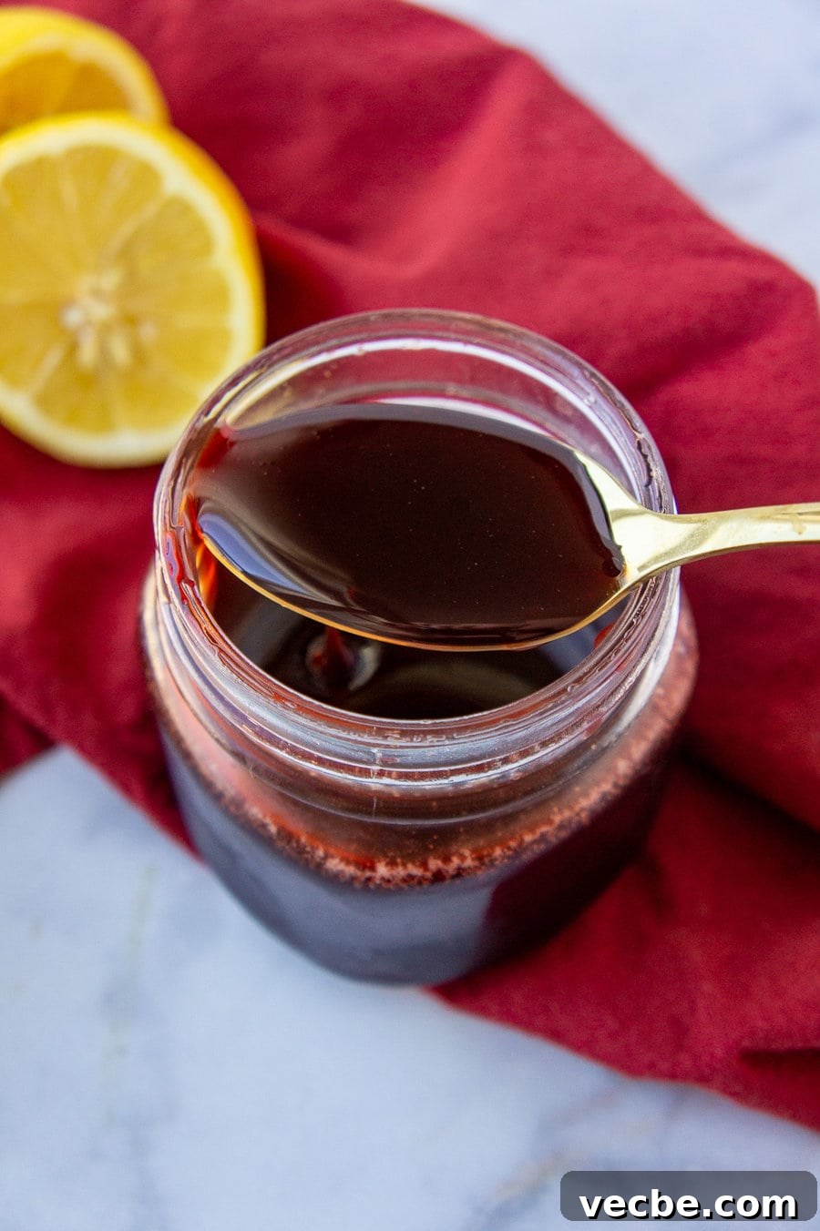 How to Make Pomegranate Molasses from Scratch 4 a spoon full of pomegranate molasses across a storage jar.