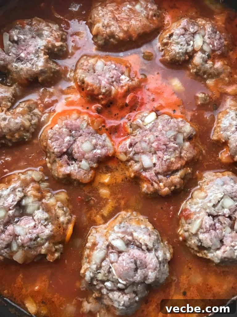 Moroccan Kefta Meatballs in Spiced Tomato Sauce 5 Kofta meatballs with chopped onions cooking in tomato sauce.