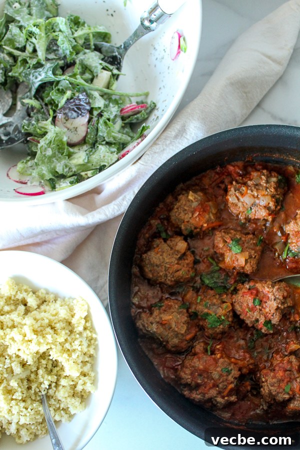 Moroccan Kefta Meatballs in Spiced Tomato Sauce 7 Kefta meatballs in a rich tomato sauce topped with chopped parsley in a saucepan.