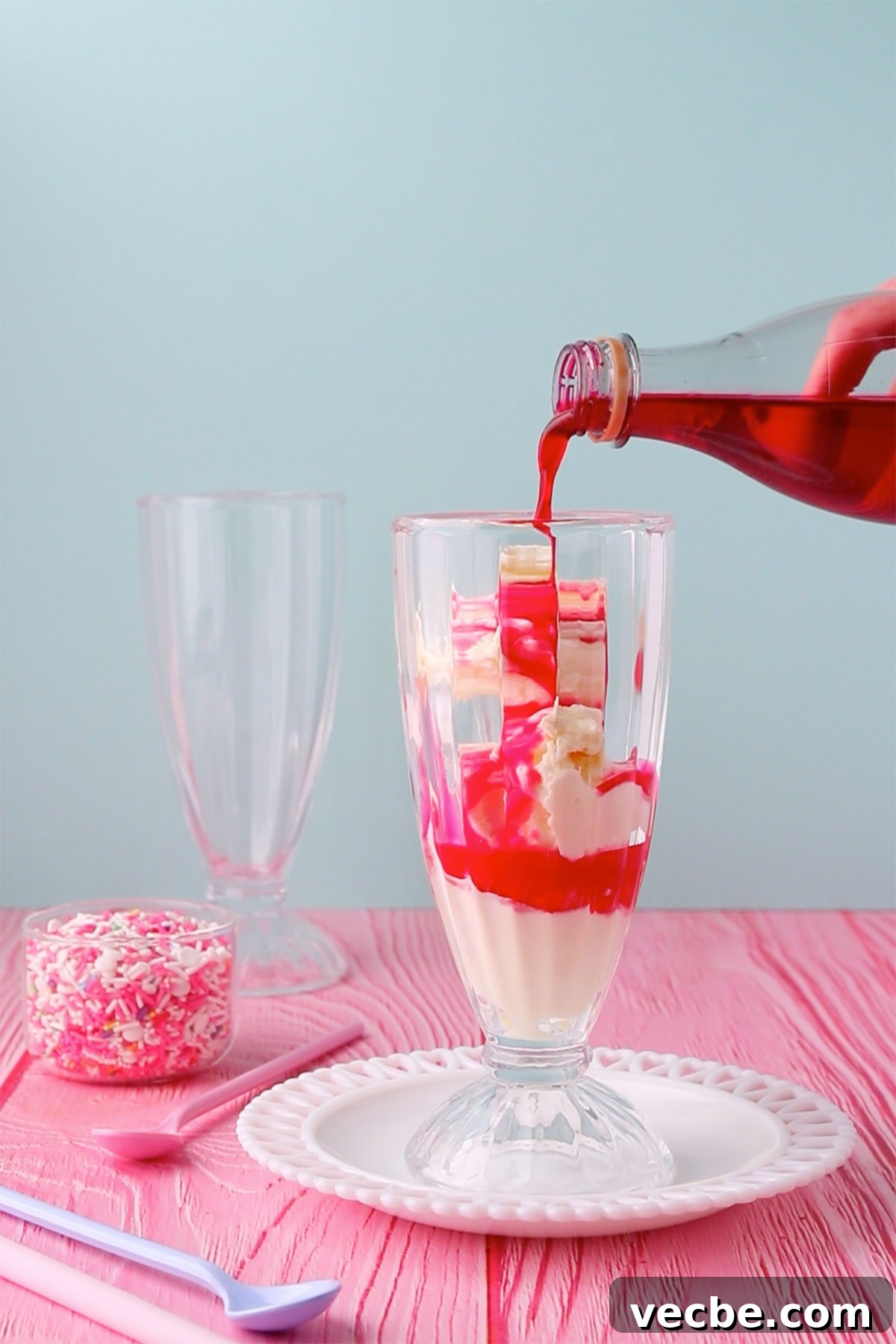 Pink Panther Raspberry Lemonade Ice Cream Float Recipe 3 A tall glass with a scoop of ice cream and some raspberry cordial being poured on top.