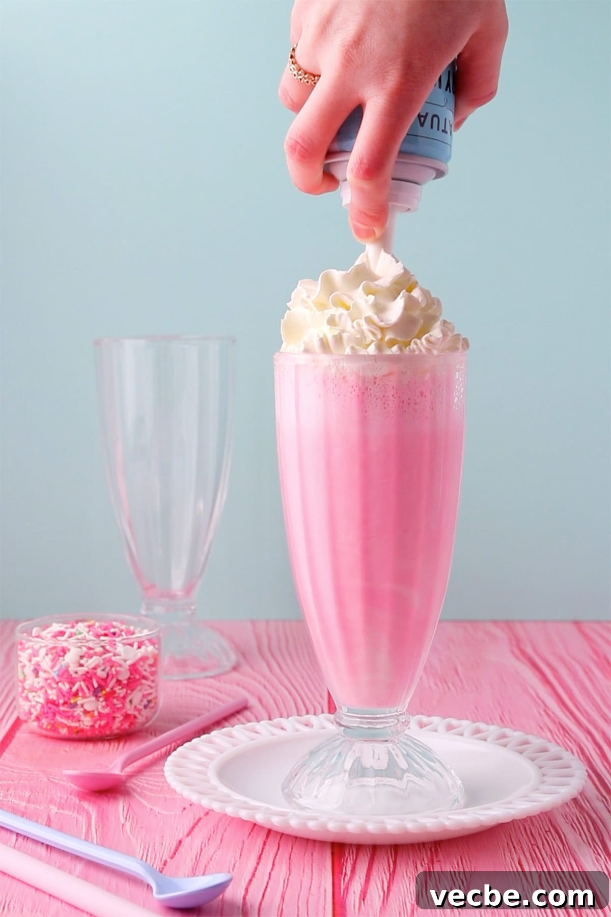 Pink Panther Raspberry Lemonade Ice Cream Float Recipe 6 A hand adding whipped cream from a can onto the top of the drink.