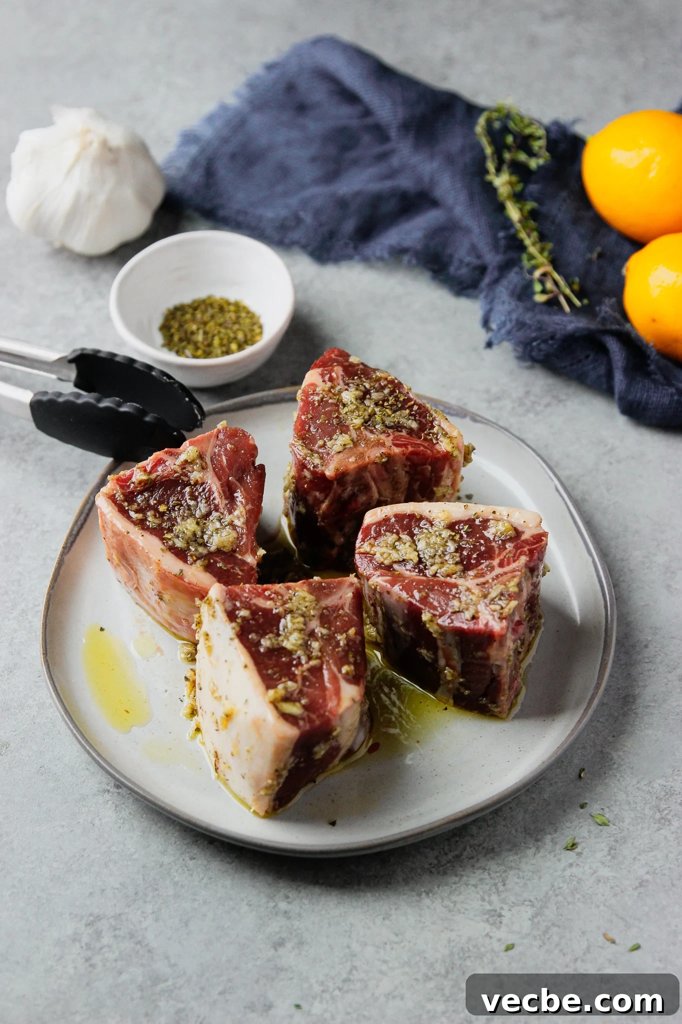 Pan-Seared Garlic & Herb Lamb Loin Chops 5 marinated lamb loin chops on a white plate.