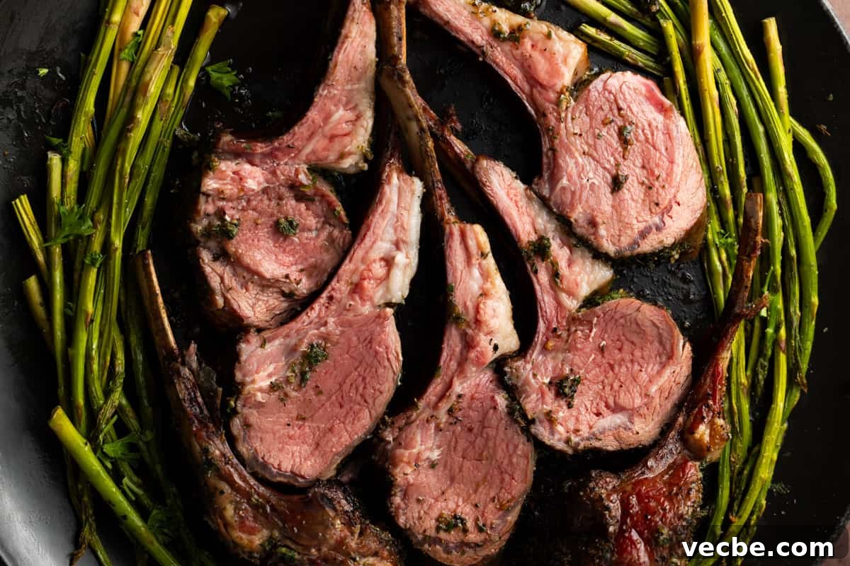 Five lamb chops on black platter surrounded by grilled asparagus.