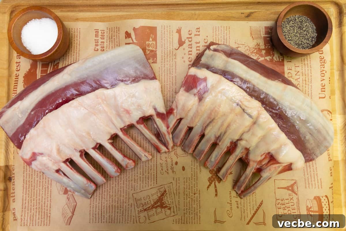 Smoked Lamb Chops Recipe with Garlic and Rosemary 4 Two racks of lamb on wood cutting board with a small dish with salt and pepper.