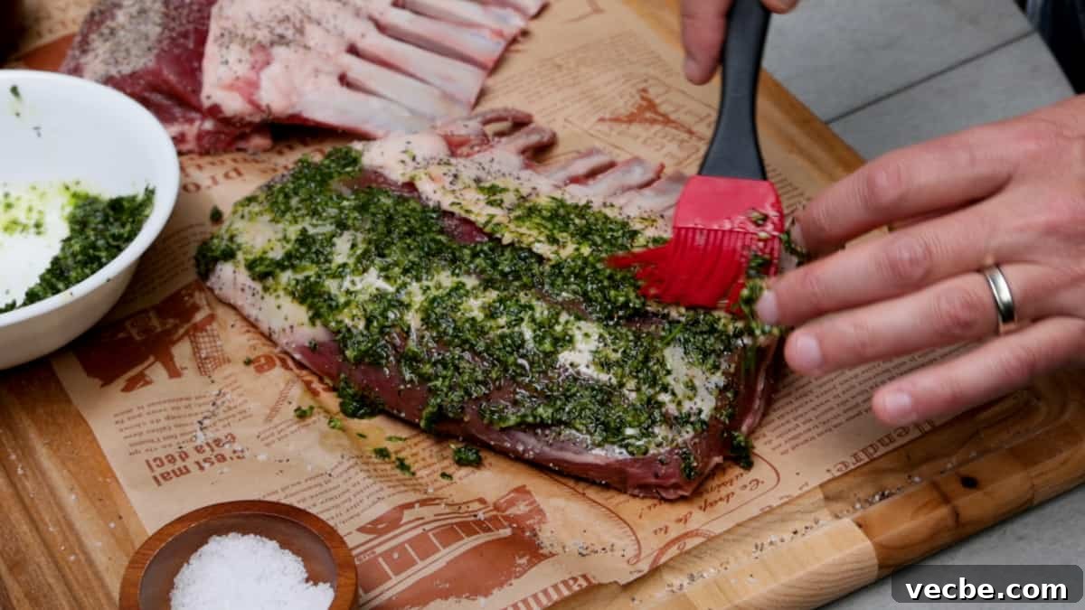 Smoked Lamb Chops Recipe with Garlic and Rosemary 5 Adding marinade to lamb chops atop a wood cutting board by hand.