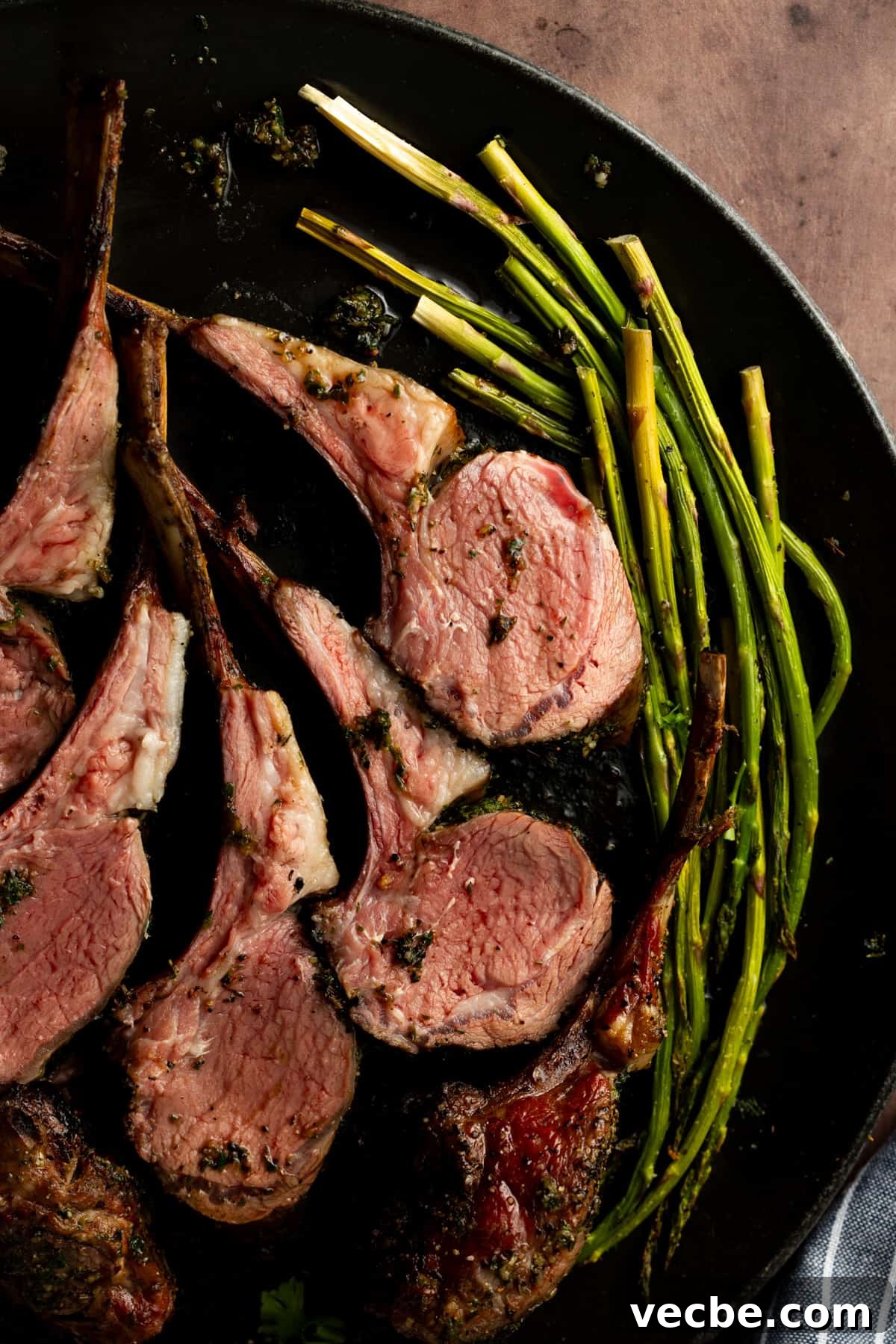 Smoked Lamb Chops Recipe with Garlic and Rosemary 9 Lamb chops on black plate with a side of asparagus.